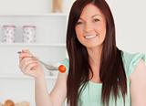 Good looking red-haired woman cutting eating a cherry tomato in 