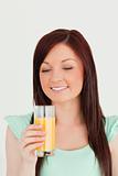Gorgeous red-haired woman enjoying a glass of orange juice in th