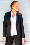 Smiling business woman standing near office building 
