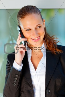 Portrait of smiling business woman talking on mobile at office building  

