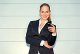 Smiling  business woman holding mobile in hand near office building 
