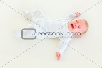 Crying four month old  baby laying on back
