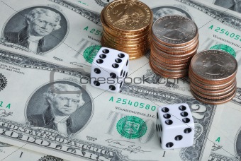 Two dices with stacks of quarters, dollar coins, and $2 bills