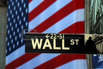 Street sign for Wall Street with the American Flag at the background