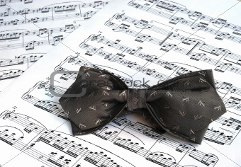 A gray bow tie on the top of music sheets