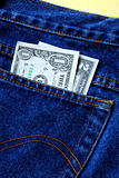 Money in the rear pocket of a blue jeans isolated on yellow