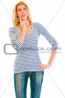 Pensive beautiful teen girl with hand near face looking up at copy-space
