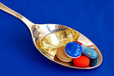 A spoonful of medicine including painkiller and vitamin isolated on blue