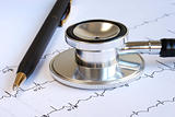 A stethoscope and a pen on the top of the EKG graph