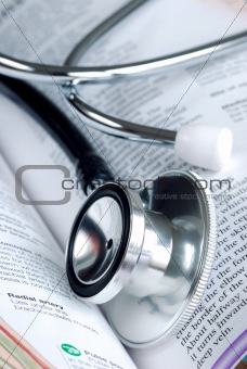 A stethoscope on the top of a medical reference book