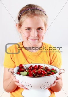 Child holding a bowl of fresh cherries