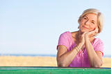 Thoughtful Attractive Senior Woman Sitting Outside at Table