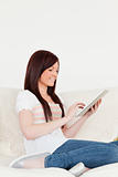 Beautiful red-haired woman relaxing with her tablet while sittin