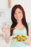 Good looking red-haired woman enjoying a mixed salad in the kitc