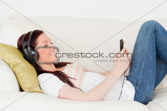 Beautiful red-haired woman listening to music with headphones wh