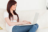 Beautiful red-haired woman relaxing with her laptop while sittin