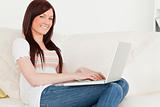 Pretty red-haired woman relaxing with her laptop while sitting o