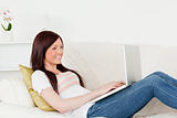 Good looking red-haired woman relaxing with her laptop while lyi