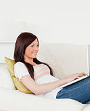 Charming red-haired woman relaxing with her laptop while lying o