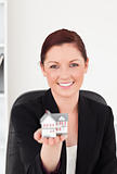 Attractive red-haired woman in suit holding a miniature house