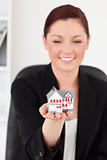 Beautiful red-haired woman in suit holding a miniature house