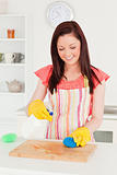 Good looking red-haired woman cleaning a cutting board in the ki