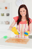 Attractive red-haired woman cleaning a cutting board in the kitc