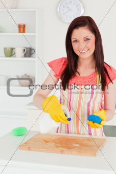 Attractive red-haired woman cleaning a cutting board in the kitc