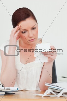 Young attractive red-haired female being depressed by the amount
