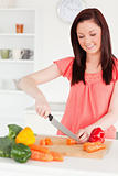 Attractive red-haired woman cutting some carrots in the kitchen