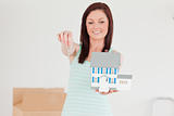 Pretty red-haired female holding a miniature house while standin