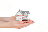 Hands holding a miniature house on a white background