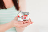 Woman holding a miniature house while standing