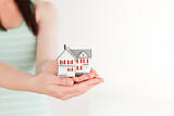 Female holding a miniature house while standing