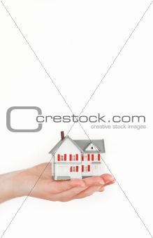 Hand holding a miniature house on a white background