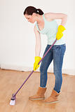Beautiful red-haired woman sweeping the floor at home