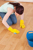 Good looking red-haired woman cleaning the floor while kneeling
