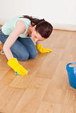 Pretty red-haired woman cleaning the floor while kneeling
