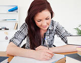 Gorgeous red-haired female studying at her desk