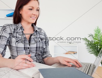 Young attractive red-haired girl relaxing with a laptop while st