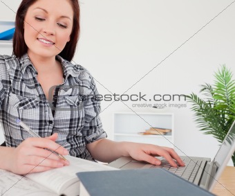 Young cute red-haired girl relaxing with a laptop while studying