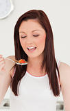 Young attractive red-haired woman eating a strawberry in the kit