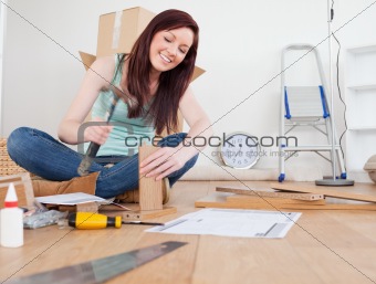 Good looking red-haired female nailing a plank at home