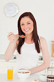 Good looking red-haired woman having her breakfast in the kitche