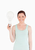 Gorgeous red-haired female holding a bulb while standing