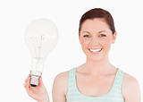 Attractive red-haired female holding a bulb while standing