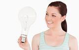 Attractive red-haired female holding a light bulb while standing