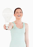 Beautiful red-haired female holding a bulb while standing 