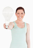 Beautiful red-haired female holding a light bulb while standing