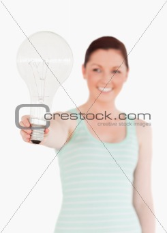 Pretty red-haired female holding a bulb while standing
